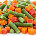 Tropical Crop Preservation: Drying and Freezing tropical crop preservation: A vibrant pile of individually quick frozen (IQF) mixed tropical vegetables, including diced bell peppers, green beans, and carrots, is displayed against a clean white background. The image emphasizes the convenience and quality of IQF technology for preserving the freshness and individual pieces of tropical produce.