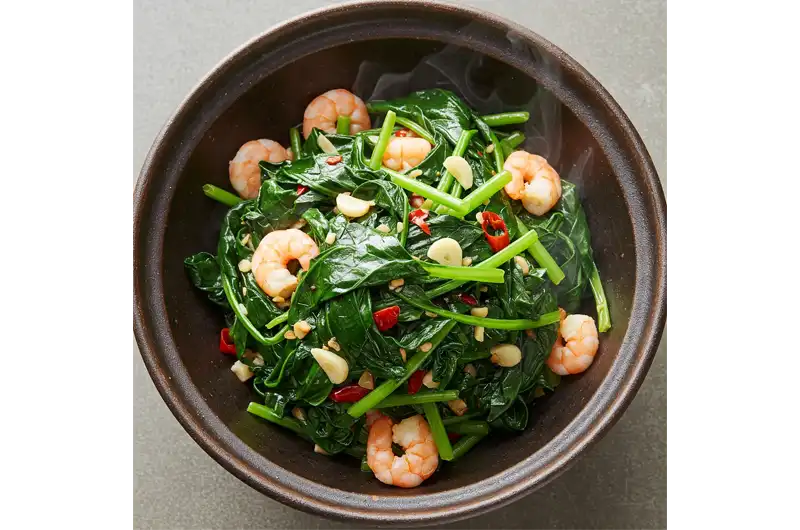 Delicious bowl of freshly stir-fried Malabar Spinach with garlic and chili, illustrating a popular culinary use for this vegetable.