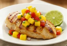Chicken Mango Salsa Recipe: Easy & Fresh Sliced pan-seared chicken breast topped generously with fresh, colorful mango salsa on a white plate.